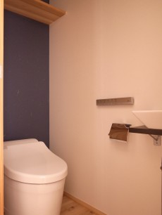 1Fトイレ。便器背面は濃紺色の和紙クロス。